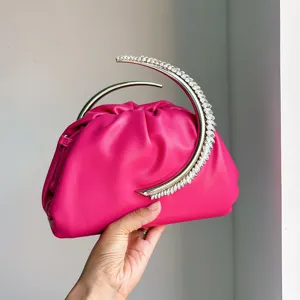 Close-up detail of the striking pink pleated evening bag with a rhinestone crescent handle.