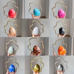 Close-up details of the elegant egg-shaped evening bag featuring unique wavy metal handles.
