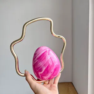 Detailed shot of pink marbled eggshell evening bag with gold irregular metal handle.
