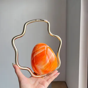 Close-up shot of the unique gradient orange eggshell evening clutch with a wavy gold handle.