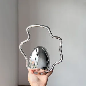 Close-up detail shot of the unique metallic egg-shaped evening bag with an irregular handle.