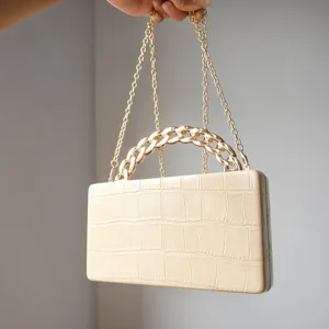 Beige crocodile pattern structured box clutch handbag with elegant gold chain handle detail.