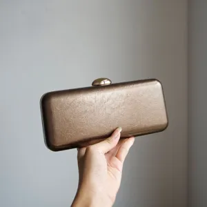 Detailed view of the elegant bronze metallic hard-case evening clutch with a chic clasp.