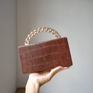 Close-up of brown crocodile pattern box handbag featuring a metallic gold chain handle.