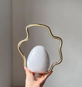 Detailed view of the French irregular evening bag with gold metal handle and gradient egg design.