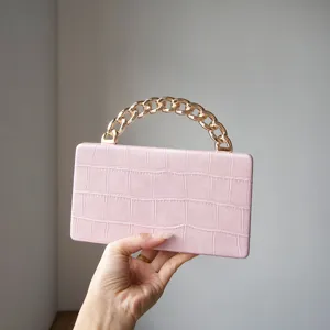 Close-up of pink crocodile texture mini handbag with chunky gold chain handle detail.