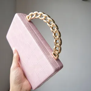 Pink crocodile pattern hard clutch bag detail, featuring a chunky gold chain handle.