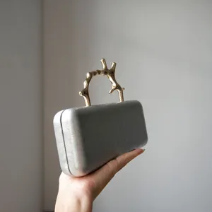 Detail view of the silver leather evening clutch showing its unique gold branch handle.