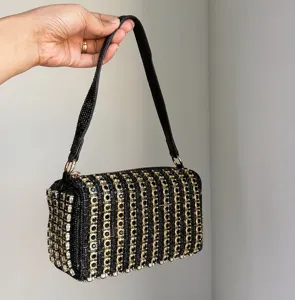 Close-up view of the luxury black rhinestone evening box bag with shining gold geometric rings.