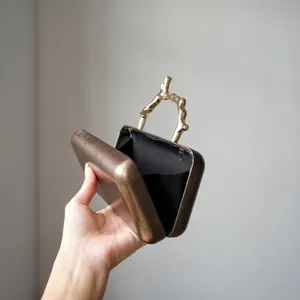 Detail shot of the luxury evening clutch bag featuring a unique gold metal branch handle.
