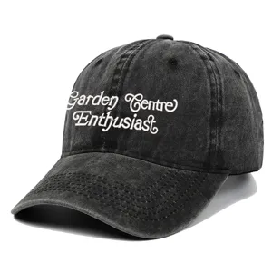 Close-up detail shot of the washed black baseball cap featuring white embroidery.