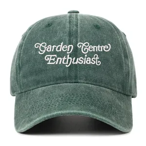 Close-up detail of the vintage washed green baseball cap featuring neat white embroidery text.