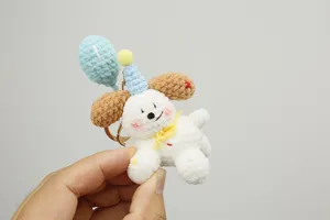 Handmade crochet puppy detail showing the cute blue balloon, party hat and soft yarn texture.