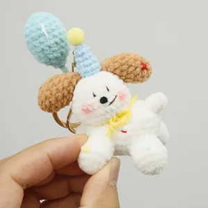 Handmade crochet puppy keychain with balloon and party hat, cute yarn bag charm for gifts.