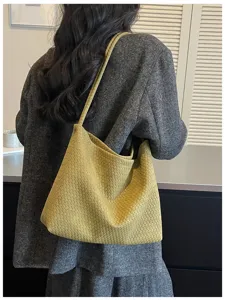 Vue détaillée du sac porté épaule tressé avec style sous les bras classique et texture cuir.