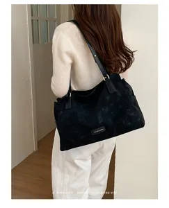 Detailopname van zwarte suède shopper tas met textuur en schouderriem ontwerp
