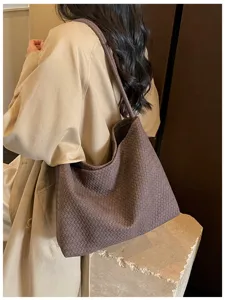 Gros plan sur l'élégant sac porté épaule tressé marron aux superbes textures de cuir.