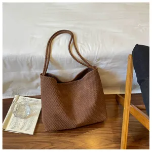 Détail du sac porté épaule marron tissé, mettant en valeur sa texture douce et ses doubles anses.