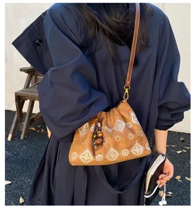 Detailed view of vintage brown suede shoulder bag with geometric embroidery and wooden beads.