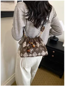 Detailed view of retro embroidered shoulder bag with wooden bead and key pendant.