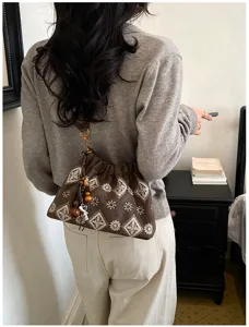 Close-up detail of vintage brown embroidered shoulder bag with bohemian bead pendant in lifestyle scene.