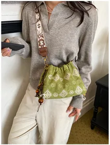 Green embroidered shoulder bag detail, ethnic strap and wooden bead pendant, casual daily use.
