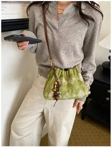 Green drawstring shoulder bag detail featuring ethnic geometric prints and beaded tassel charm.