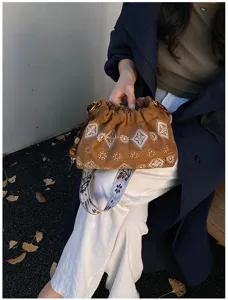 Detail view of a retro brown suede bucket bag with ethnic embroidery and wide strap.
