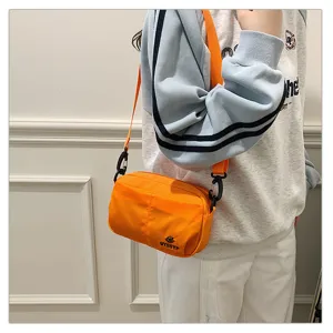 Detalle del bolso cruzado naranja llevado por el modelo para un estilo casual diario.