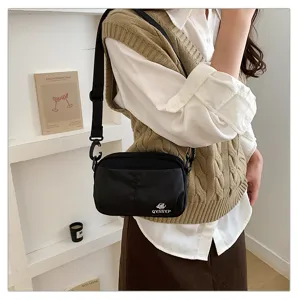 Vista detallada del bolso bandolera negro con múltiples bolsillos en el modelo, práctico.
