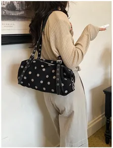 Model wearing a black polka dot fabric shoulder bag with leather straps and silver metal eyelets