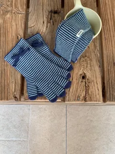 Primer plano del conjunto de bufanda y guantes de punto a rayas azules con lazo para el invierno.