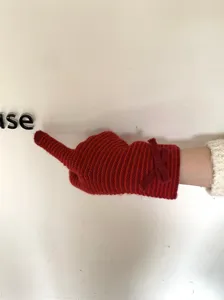 Detalle de guante de punto rojo con patrón de rayas y bonito lazo para invierno.