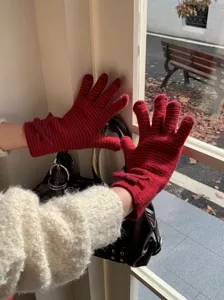 Vista detallada de guantes de punto a rayas rojas de invierno para mujer con lazo.