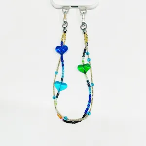 Détail de la lanière de téléphone perlée à design multicouche, cœurs en verre et clips.