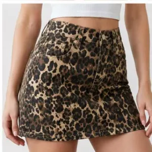 Leopard print denim mini skirt detail shot, high waist A-line bodycon fit showcasing pattern texture.