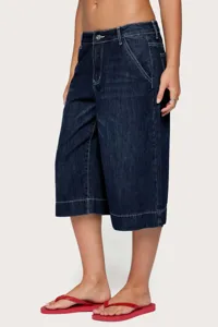 Detailed view of women's dark blue denim capri pants, loose straight leg fit, white stitching.