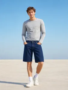 Vue rapprochée d'un short en jean décontracté porté avec un haut gris à l'extérieur.