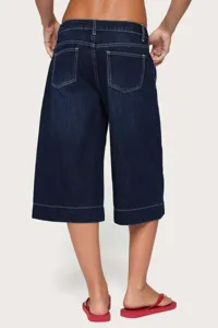 Back view details of women's dark wash denim capris featuring contrast white stitching and loose fit.