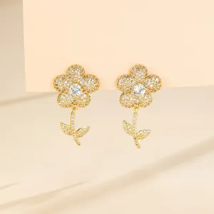 Vue détaillée de boucles d'oreilles fleurs plaquées or scintillantes de zircons sur carte.