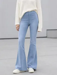 Detail shot of light blue high-waisted flare jeans paired with a white casual knit sweater.