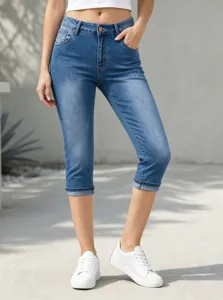 Primo piano di jeans capri blu a vita alta elasticizzati con classica finitura di lavaggio.