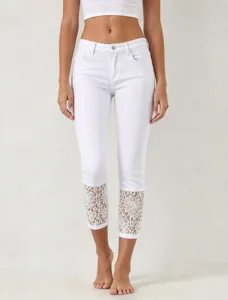 Detail view of white cropped denim jeans featuring delicate lace cuffs and slim fit design.