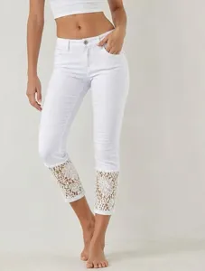 Detail view of women white cropped denim jeans with delicate lace cuffs and stretch fabric.