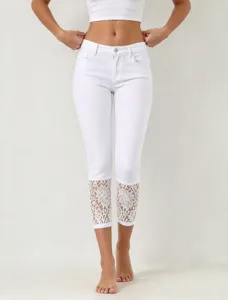 Detail view of women's white cropped jeans featuring delicate lace cuffs and stretch denim.