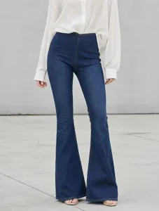 Detailed view of women's dark blue high-waisted stretch flare jeans worn with white top.