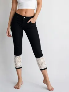Women black cropped jeans with white lace cuffs, stylish washed denim pants detail view.
