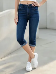 Dettaglio di pantaloni capri in denim elasticizzato blu, vita alta e orlo risvoltato.