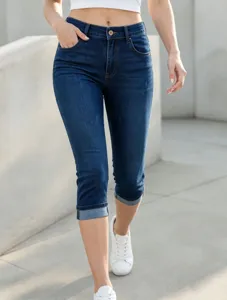 Primo piano dettagliato di pantaloni capri da donna in denim blu scuro con risvolti.