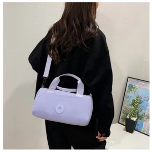 Vue détaillée d'un élégant sac coussin cylindrique violet clair avec un badge rond.